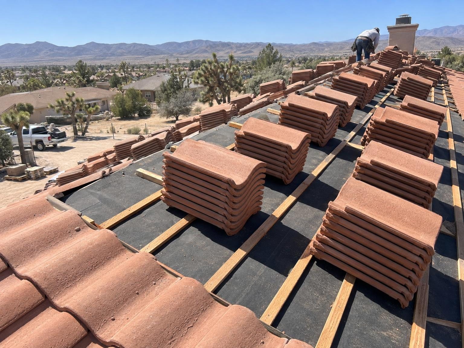 Terracotta concrete roof tiles stacked on battens over black underlayment, ready to lay